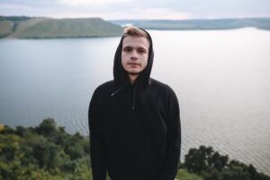 Hipster traveler in windbreaker standing alone on top of rock mountain