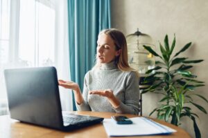 Young teacher with computer having video conference chat with student